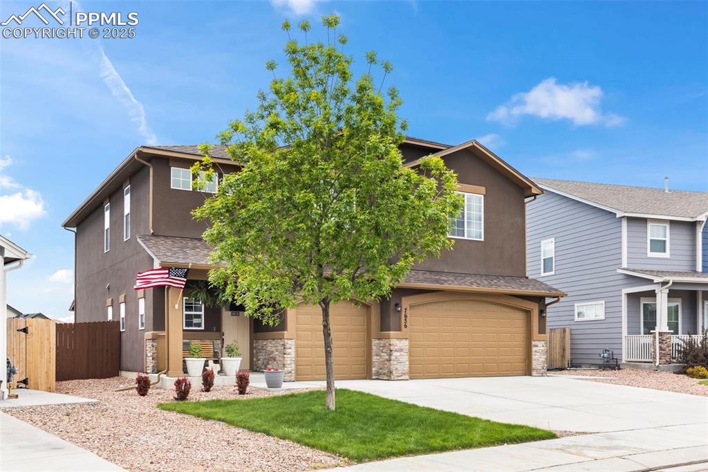 Image 3 of 45: View of front of home featuring an attached garage, stone siding, driveway,