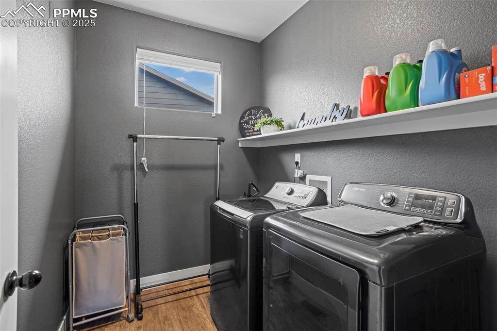 Image 36 of 45: Laundry room with separate washer and dryer, wood finished floors, and base