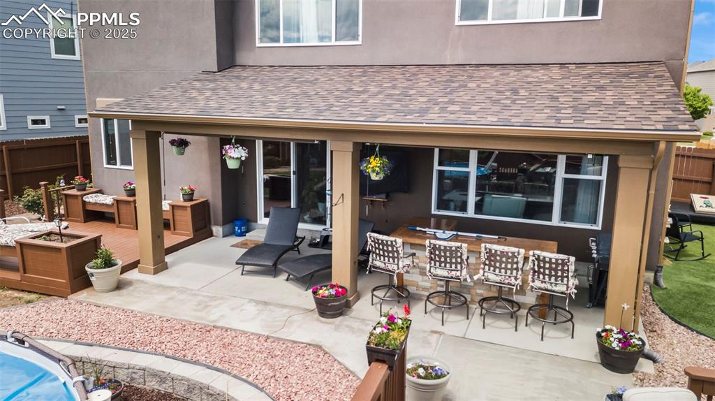 Image 9 of 45: Rear view of house featuring a patio, stucco siding, a wooden deck, and roo