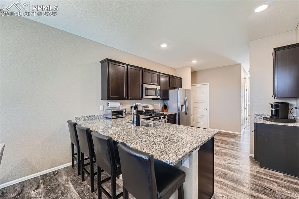 Image 11 of 32: Kitchen with appliances with stainless steel finishes, dark brown cabinets,