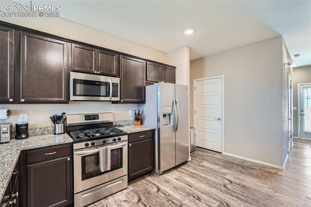 Image 12 of 32: Kitchen with appliances with stainless steel finishes, dark brown cabinetry