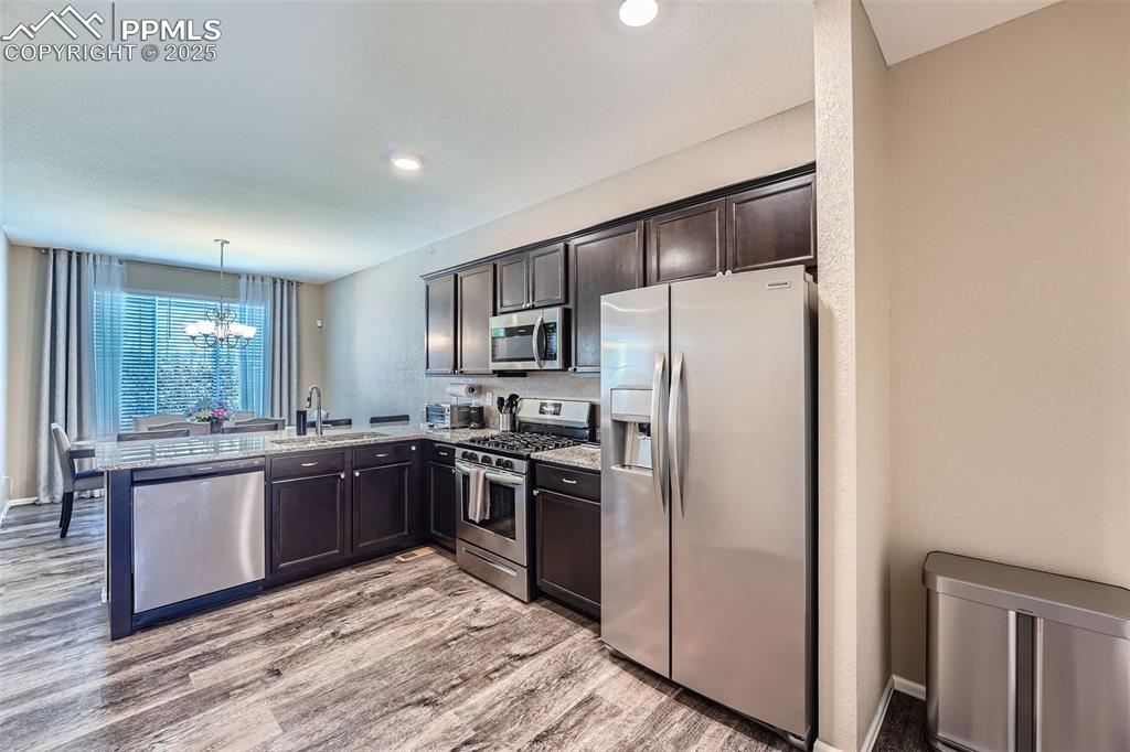 Image 15 of 32: Kitchen featuring appliances with stainless steel finishes, a chandelier, l