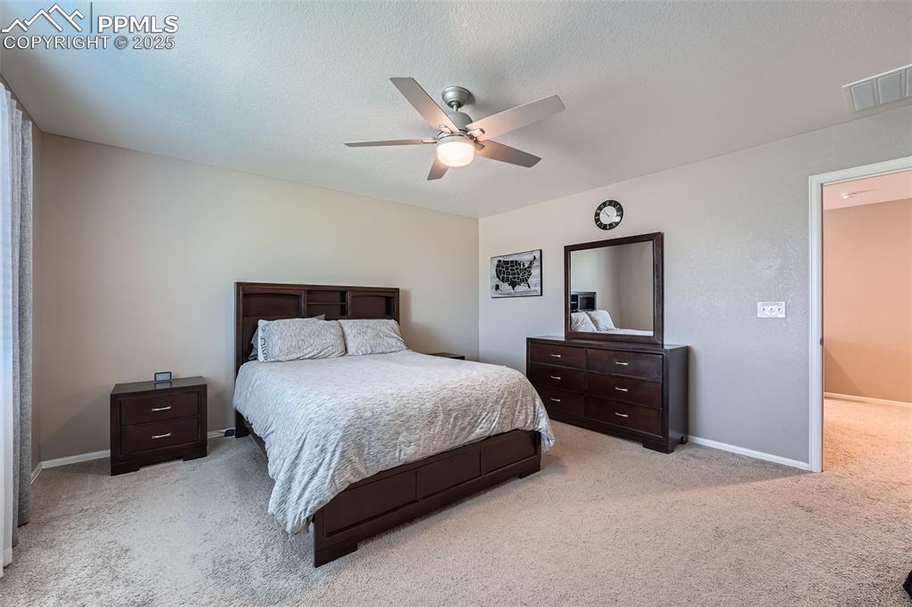 Image 18 of 32: Primary Bedroom with light carpet, ceiling fan, and a textured ceiling
