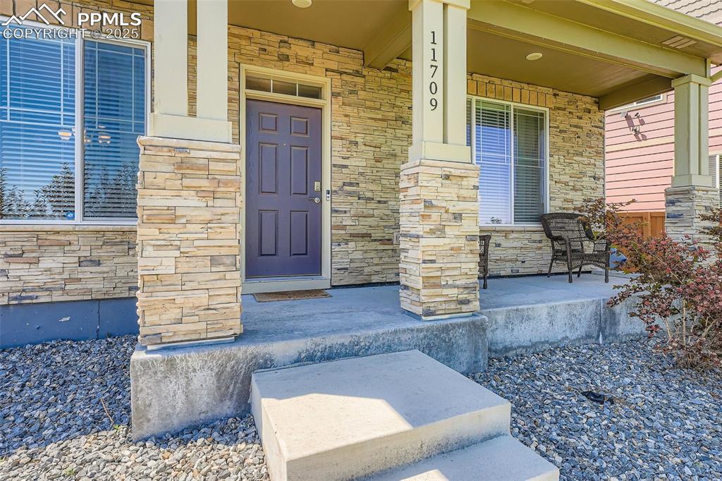 Image 2 of 32: View of exterior entry featuring covered porch and stone siding