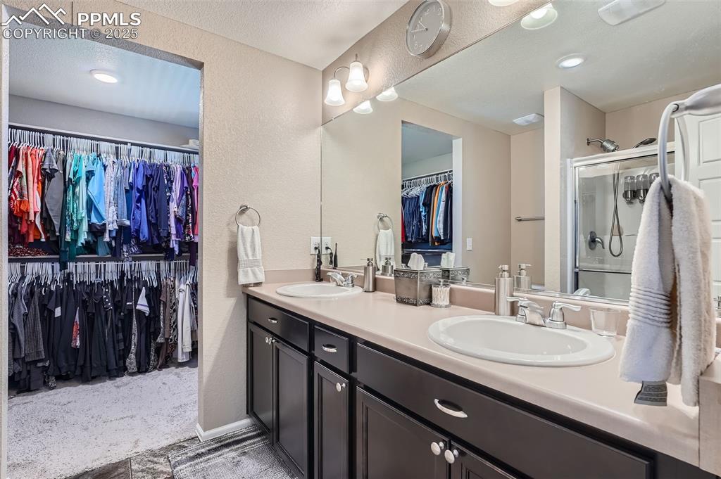 Image 20 of 32: Primary bathroom featuring a spacious closet, double vanity, a textured wal