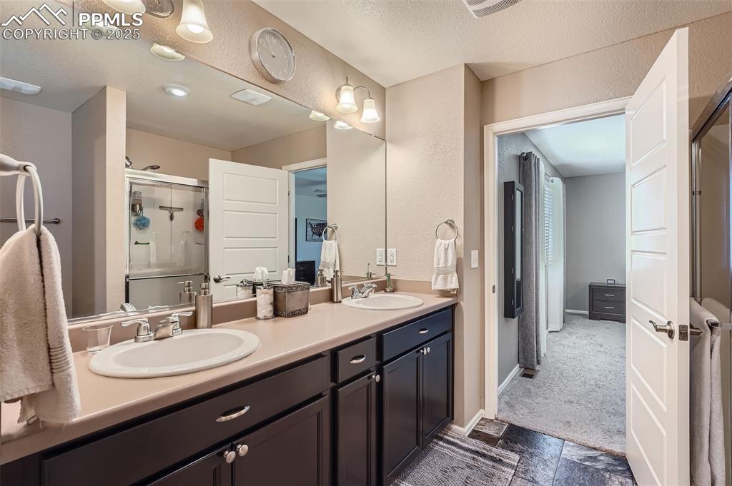 Image 21 of 32: Primary bathroom featuring a stall shower and double vanity