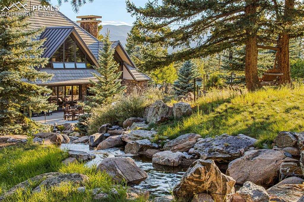 Image 27 of 38: A peaceful stream flowing straight to the back patio and emptying into the 