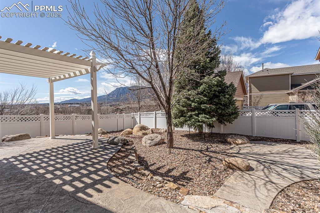 Image 40 of 49: View of yard featuring a mountain view, a patio area, a pergola, and a fenc