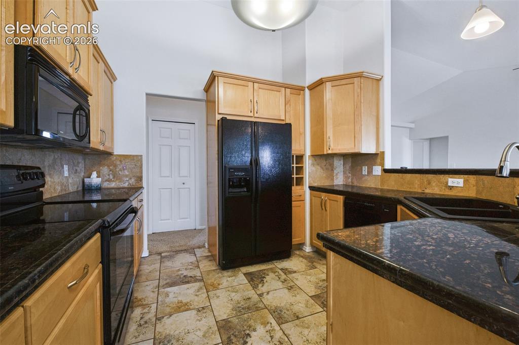 Image 13 of 50: Kitchen featuring dark countertops, light wood-finish cabinetry, black appl