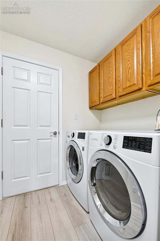Image 14 of 50: Light wood-finish flooring, white paneled door, and natural wood cabinetry