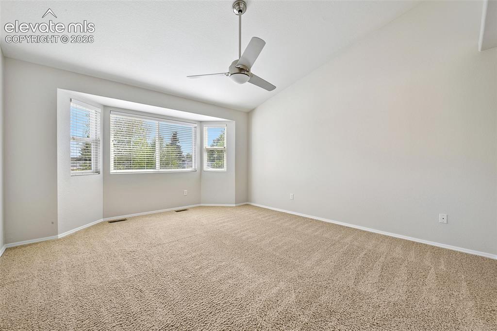 Image 15 of 50: Spacious room featuring vaulted ceilings, a large bay window, neutral carpe