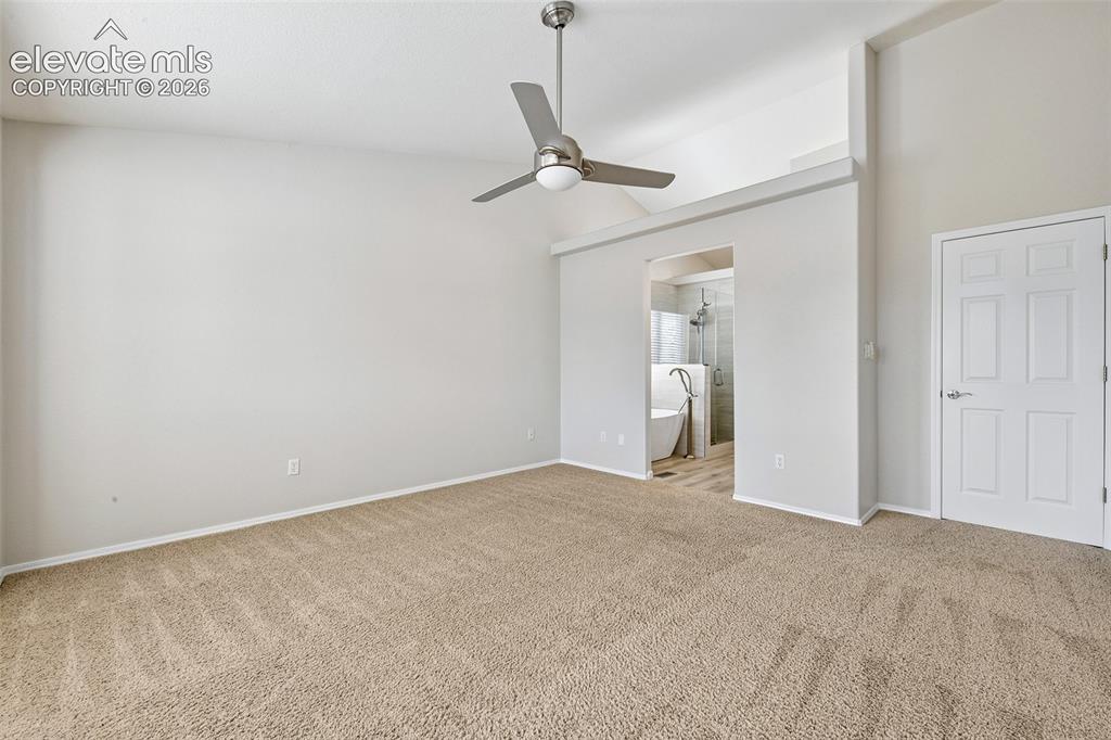 Image 16 of 50: Vaulted ceiling with an attached ceiling fan, carpet flooring, interior doo