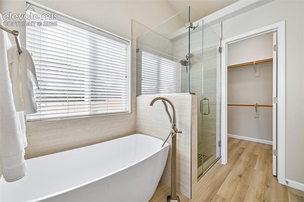 Image 19 of 50: Freestanding soaking tub with floor-mounted faucet, glass-enclosed shower,