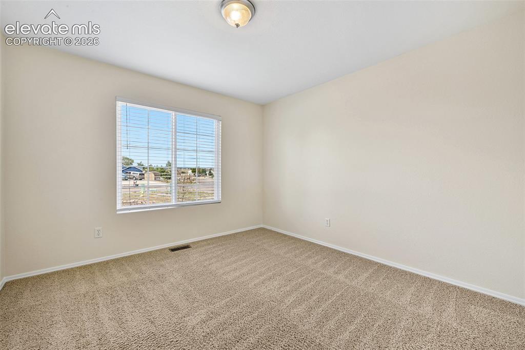 Image 21 of 50: Neutral tone wall paint, textured carpeting, window with horizontal blinds,