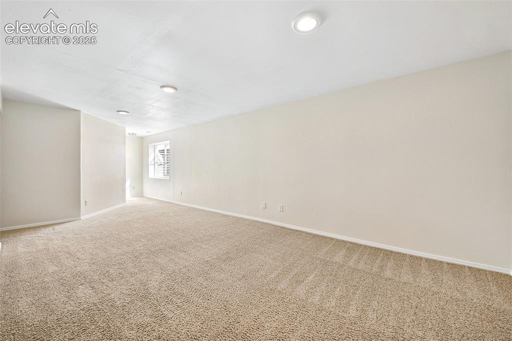 Image 26 of 50: Basement Family Room Neutral-toned walls and plush carpeting, illuminated b