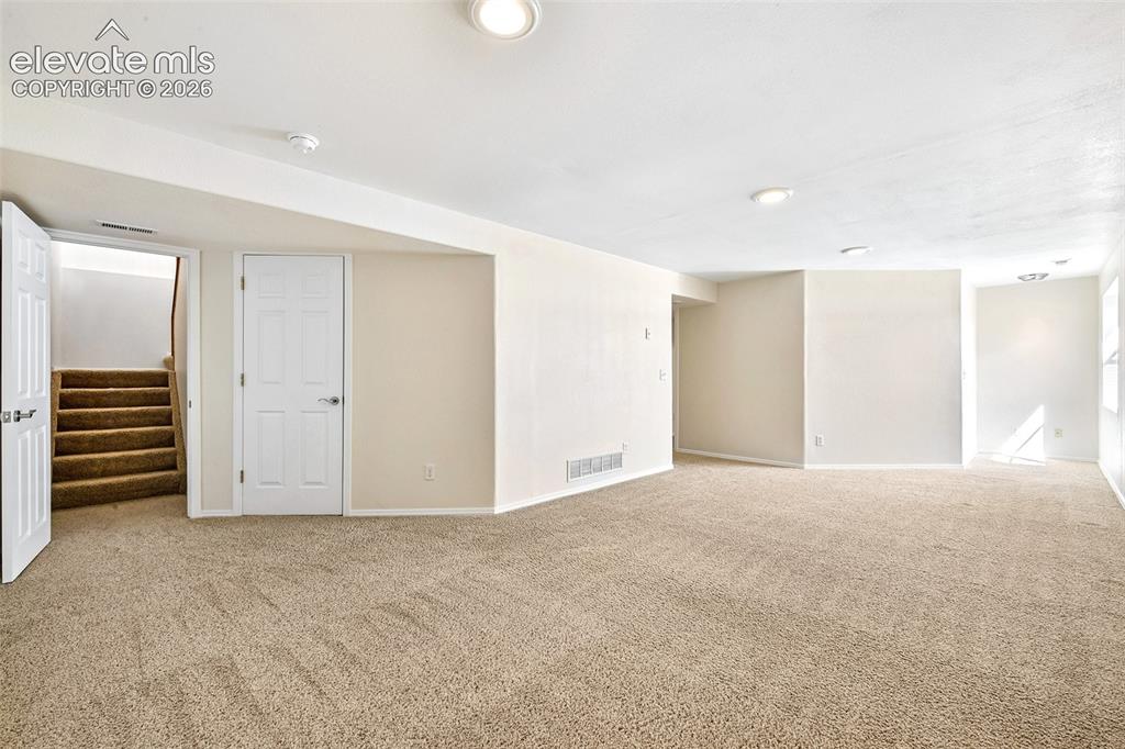 Image 27 of 50: Basement Family room Expansive carpeted area with recessed lighting and a n