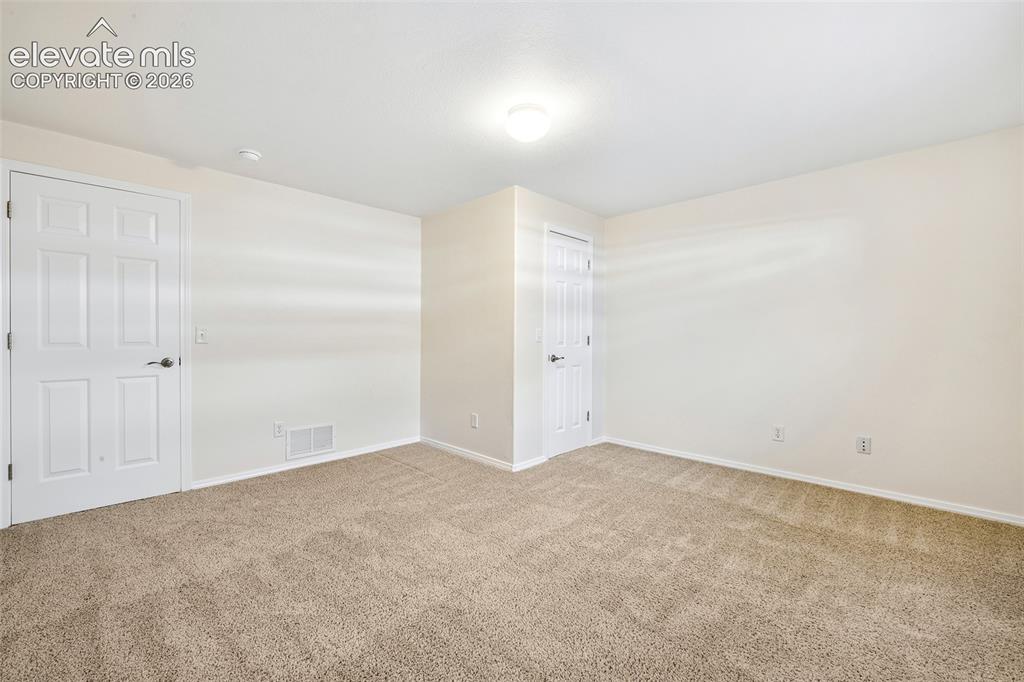 Image 31 of 50: Basement Bedroom, Neutral toned walls with carpeting