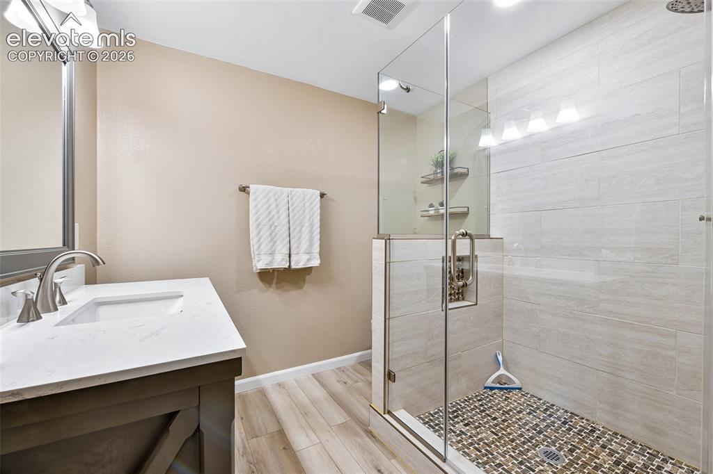 Image 32 of 50: Basement bathroom, Walk-in shower with clear glass enclosure, pebble tile f