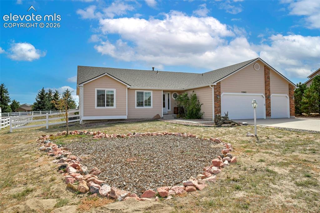 Image 34 of 50: Ranch-style residence featuring a three-car garage, white fencing, and a de