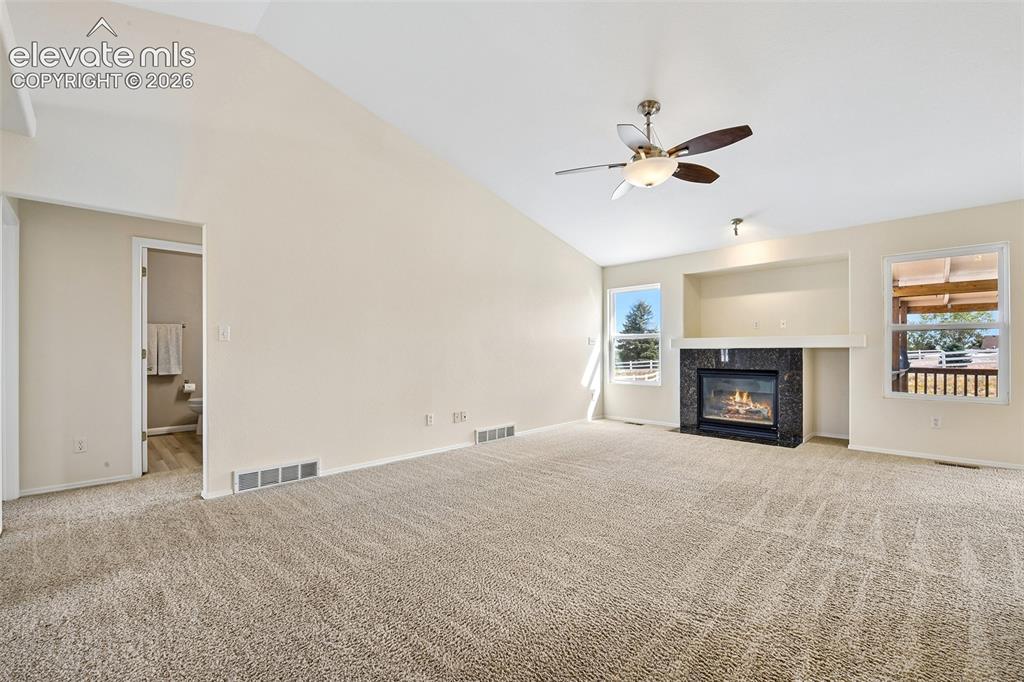 Image 6 of 50: Vaulted ceiling with ceiling fan, recessed media niche with black stone-sur