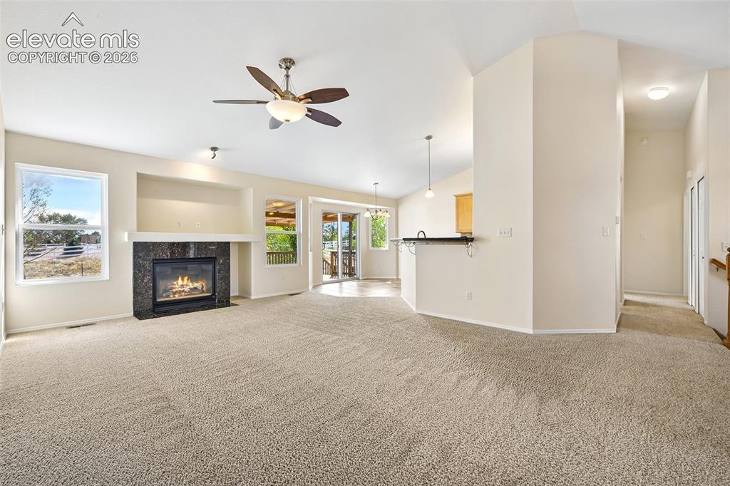 Image 7 of 50: Vaulted ceilings, a built-in fireplace with a stone surround, and an integr