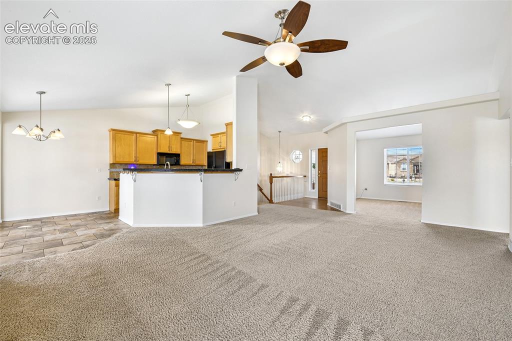 Image 9 of 50: Open-concept living area with carpet flooring and a ceiling fan