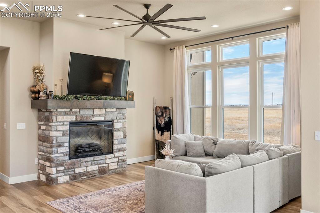Image 13 of 50: Living area features stone fireplace and ceiling fan