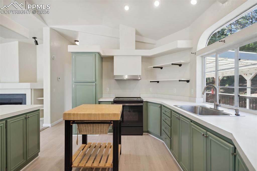 Image 15 of 32: Kitchen with lofted ceiling, green cabinets, electric range, and sink