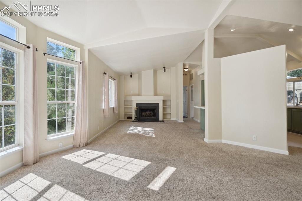 Image 8 of 32: Living room with vaulted ceiling and light carpet