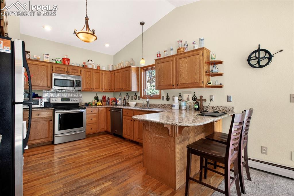 Image 15 of 43: Kitchen with stainless appliances, breakfast bar, granite counter tops and