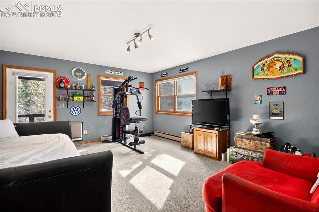 Image 30 of 43: Family room with walk out to covered lower deck with hot tub and dog run