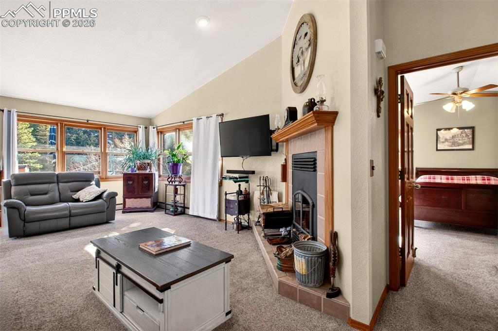 Image 8 of 43: Living room with wood burning fireplace. Also a view of the primary bedroom