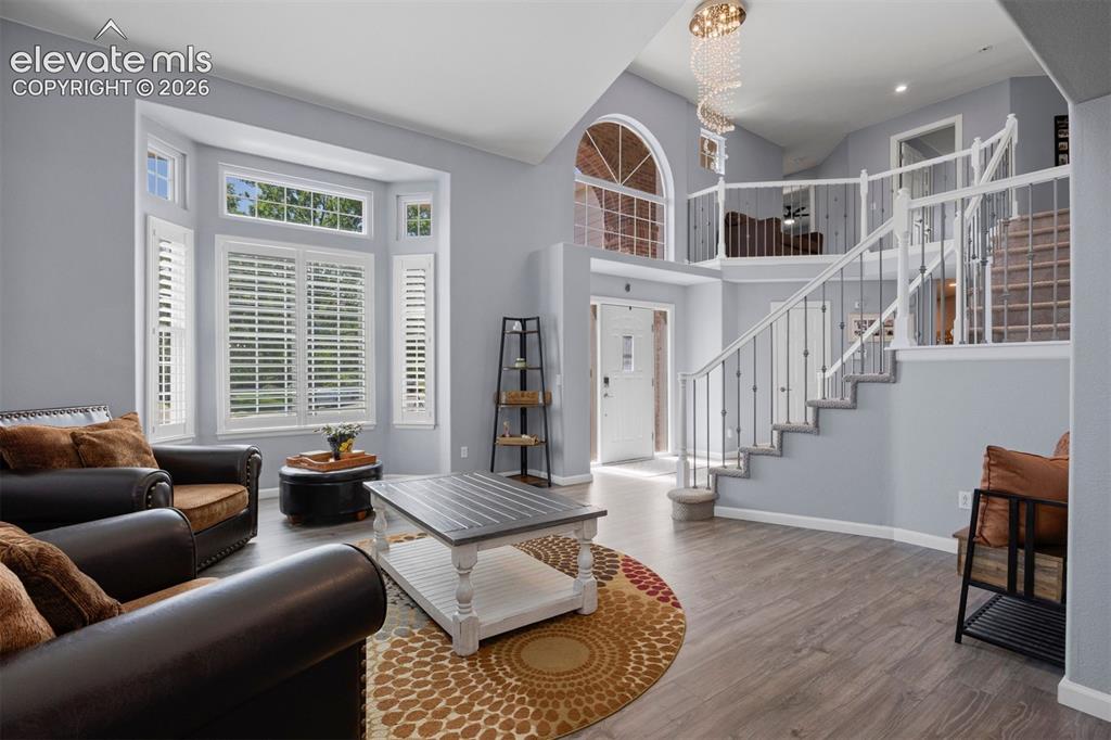 Image 12 of 50: Spacious living area featuring high ceilings, wood-finish flooring, a bay w