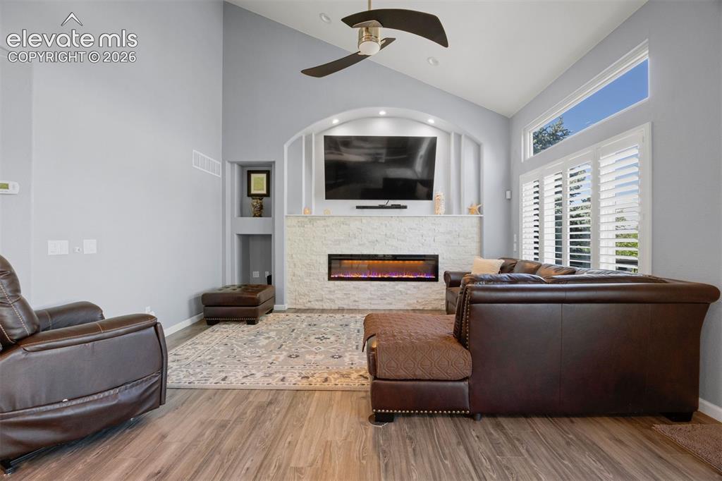 Image 19 of 50: Vaulted ceiling living space featuring wood-finish flooring, a contemporary