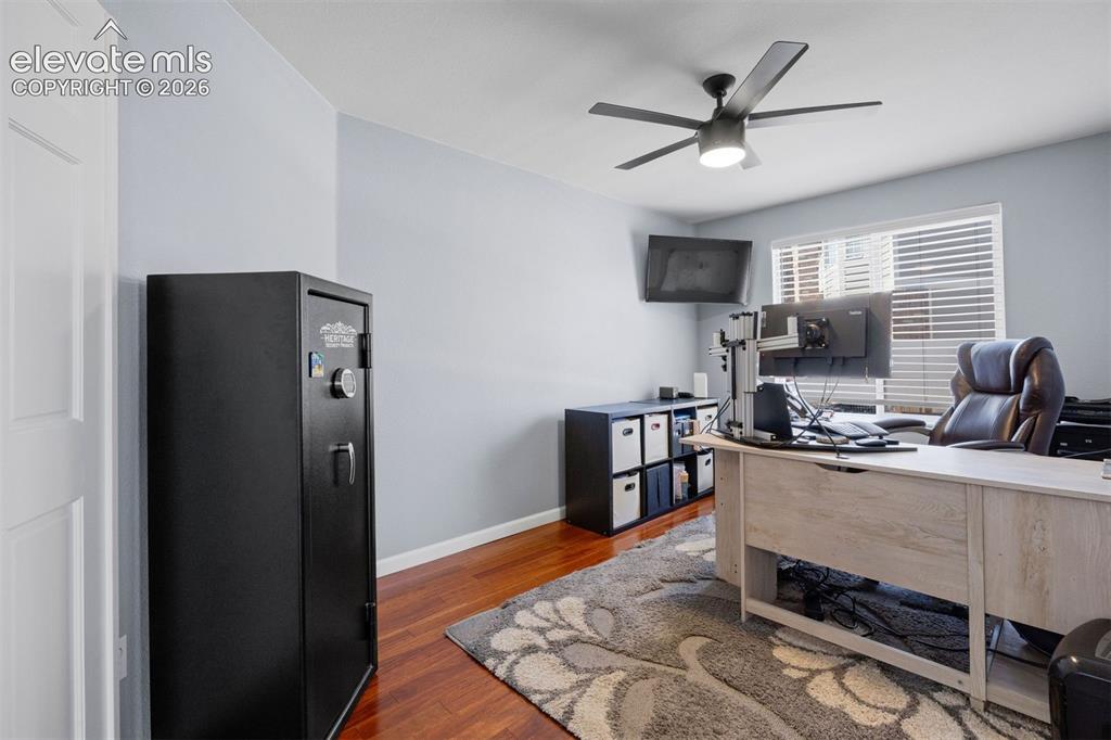 Image 23 of 50: Room with cherry wood-finish flooring, light gray walls, and a ceiling fan