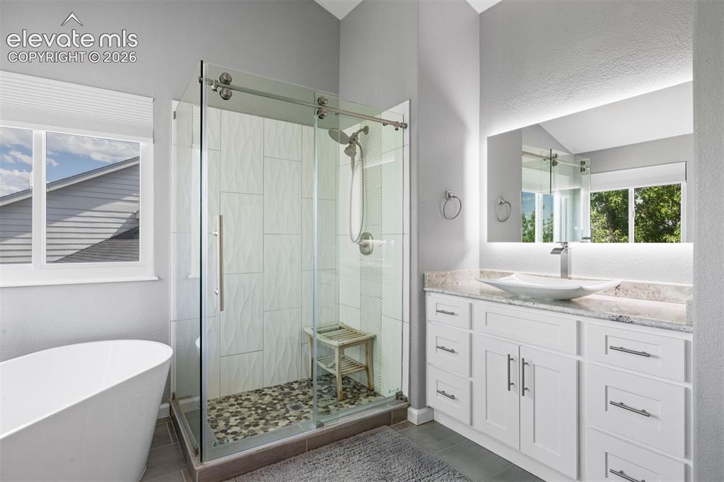 Image 30 of 50: Vanity with a vessel sink, stone countertop, and an illuminated mirror