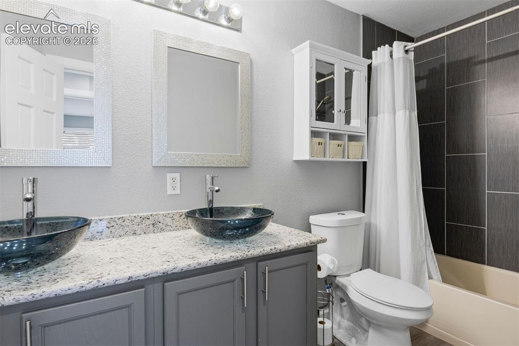 Image 33 of 50: Upstairs bathroom. Dual vessel sinks with modern chrome faucets set on a st