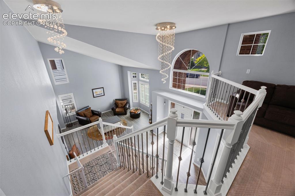 Image 35 of 50: Foyer and living area showcasing a grand staircase, vaulted ceiling, and mu