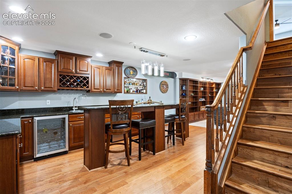 Image 36 of 50: Finished basement featuring a wet bar with cherry cabinetry, granite counte