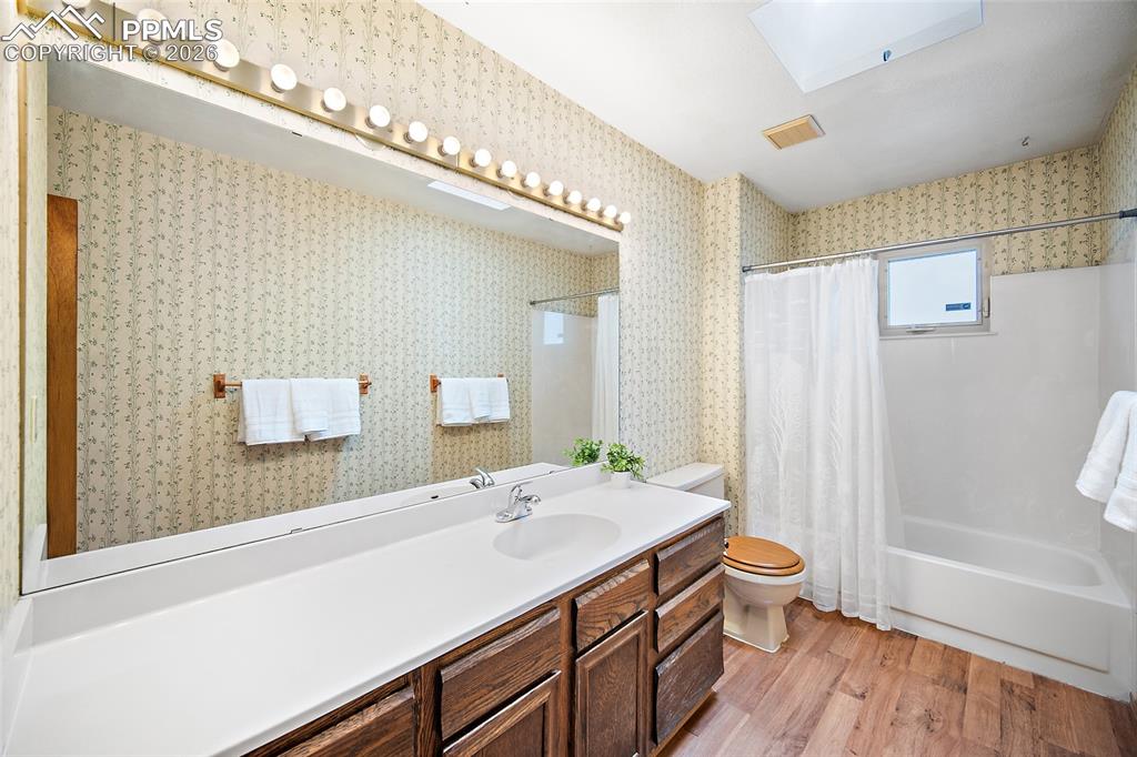 Image 14 of 40: Bathroom with vanity, light wood-style flooring, shower / tub combo with cu