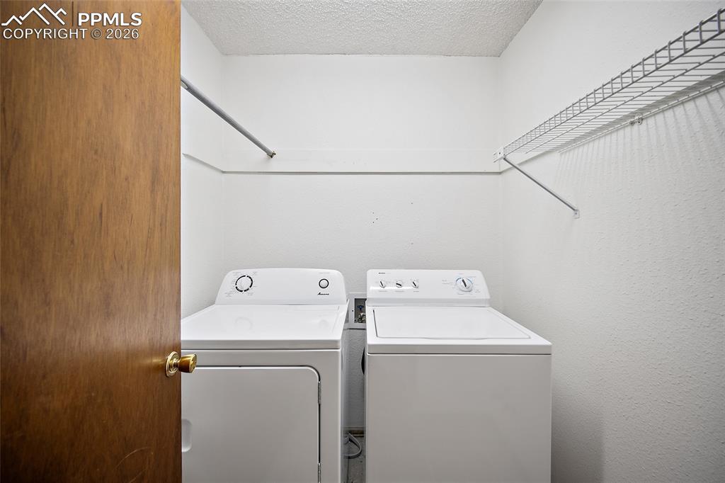 Image 19 of 40: Laundry room with a textured ceiling and washer and dryer
