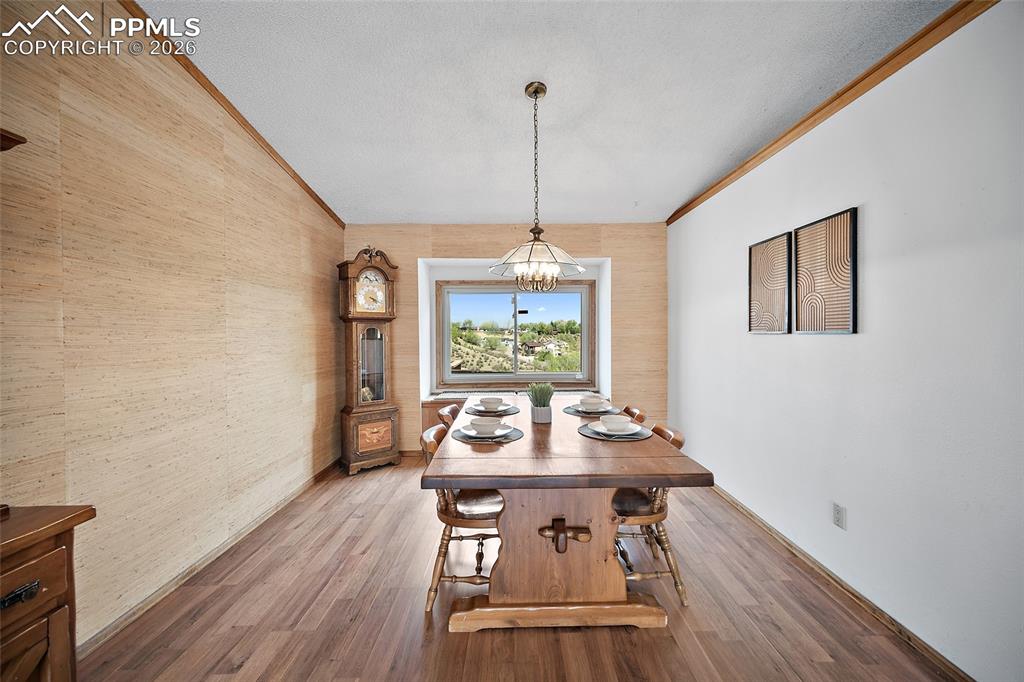 Image 6 of 40: Dining area featuring ornamental molding, wood finished floors, a textured 