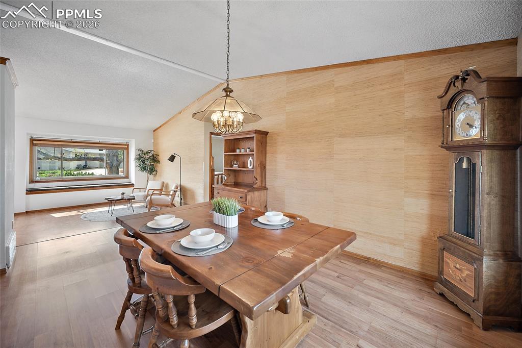 Image 7 of 40: Dining room with light wood finished floors and suspended lighting