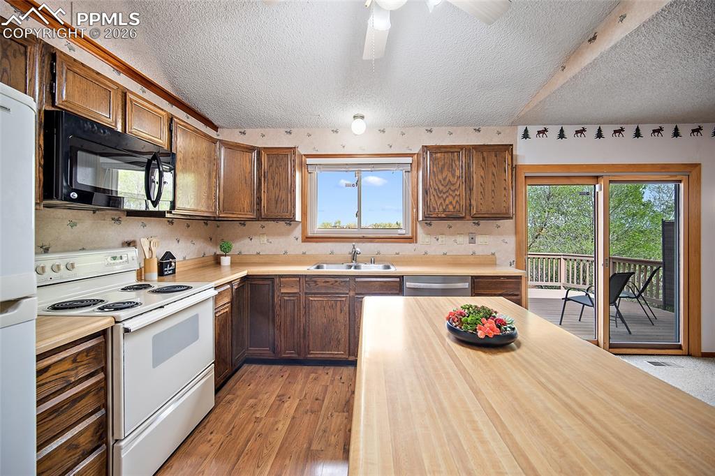 Image 8 of 40: Kitchen with white appliances, light wood-style floors, ceiling fan, a text