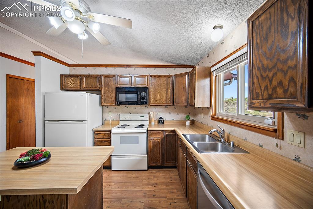 Image 9 of 40: Kitchen featuring white appliances, ceiling fan, light wood-style floors, a