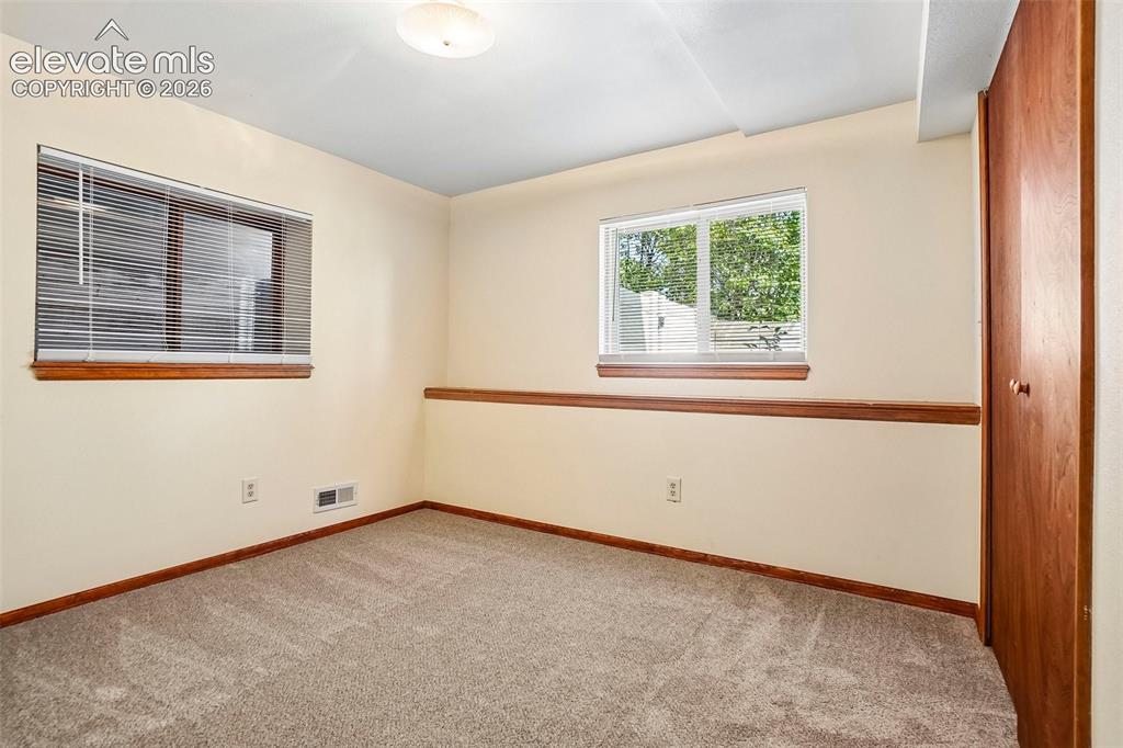 Image 21 of 48: Guest bedroom in basement has garden-level window on one side.