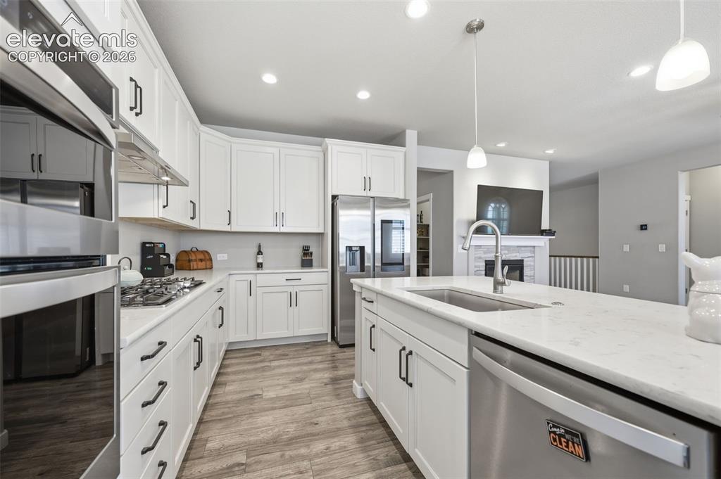 Image 11 of 43: Kitchen featuring white cabinetry, stainless steel appliances, light brown 
