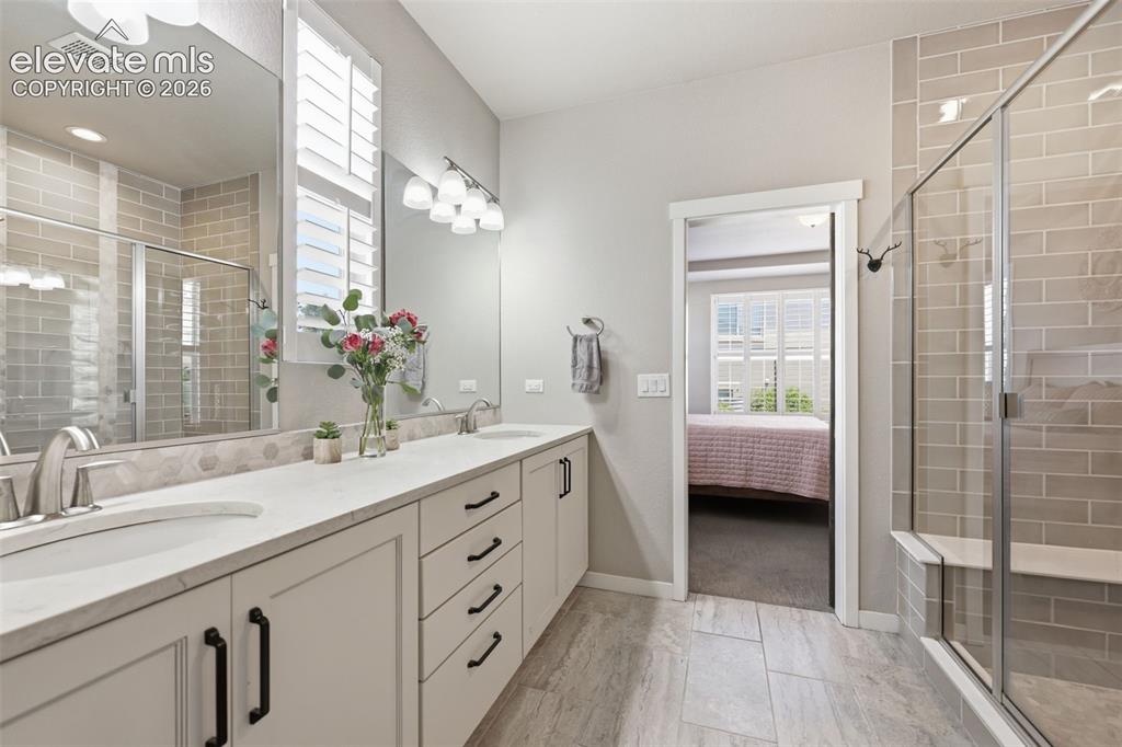 Image 20 of 43: Double vanity with undermount sinks, white stone countertops, and black cab