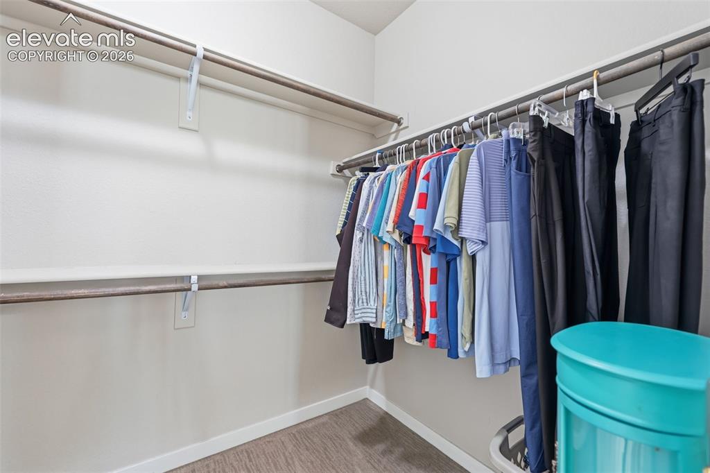 Image 21 of 43: Walk-in closet featuring built-in hanging rods and shelving.