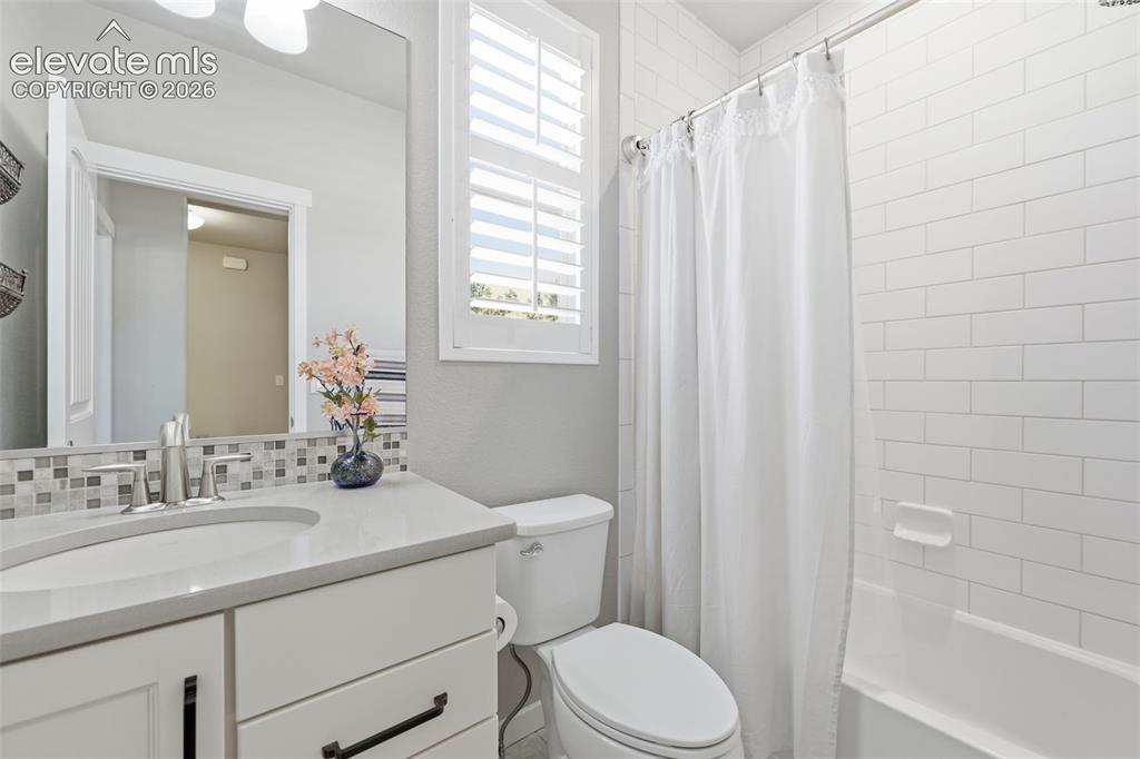 Image 23 of 43: White shaker-style vanity with a light-toned stone countertop, undermount s